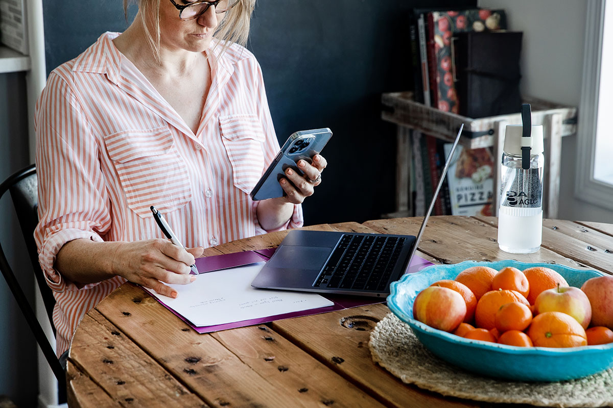 A woman sits at a table with a phone in her hand