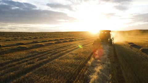 A tractor moves through a field at sunrise